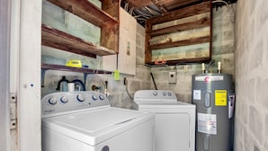 Uma lavanderia com duas máquinas de lavar Whirlpool, um aquecedor de água e vigas de madeira no teto.