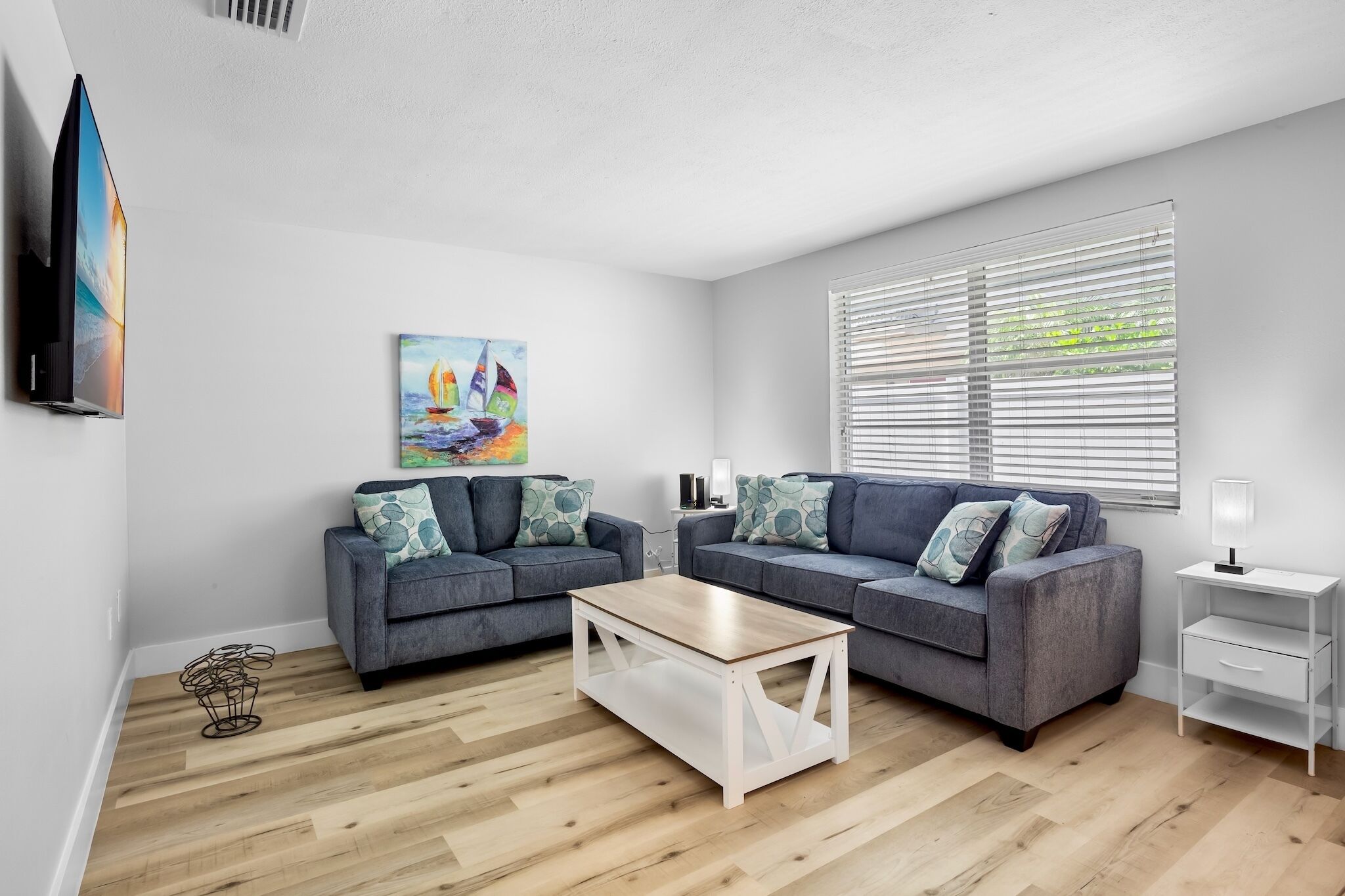 A modern living room with two grey sofas, a wooden coffee table, and a white side table.