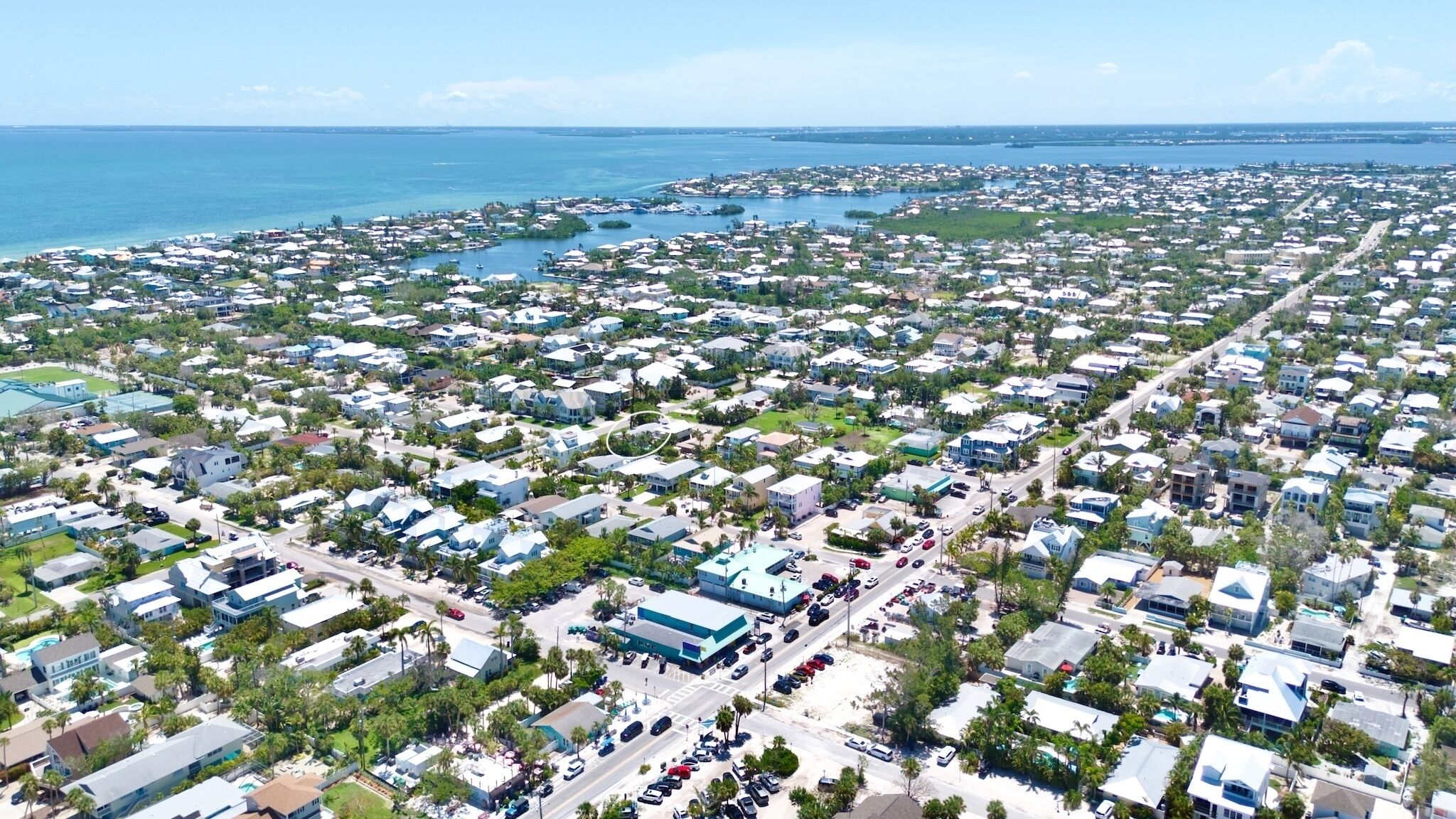 An aerial view of a coastal residential area with numerous houses, roads, and a marina.