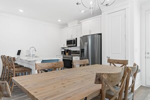 A modern kitchen with white cabinets, a stainless steel refrigerator, a microwave, and a coffee maker.