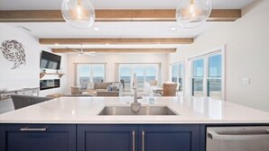 A modern kitchen with a large island, built-in appliances, and a view to the living area. - Grand new construction, gulf front, private pool, elevator, pet friendly! (Port Saint Joe)
