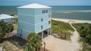 A multi-story building with a flat roof, located near a beach with a clear view of the ocean. - Grand new construction, gulf front, private pool, elevator, pet friendly! (Port Saint Joe)