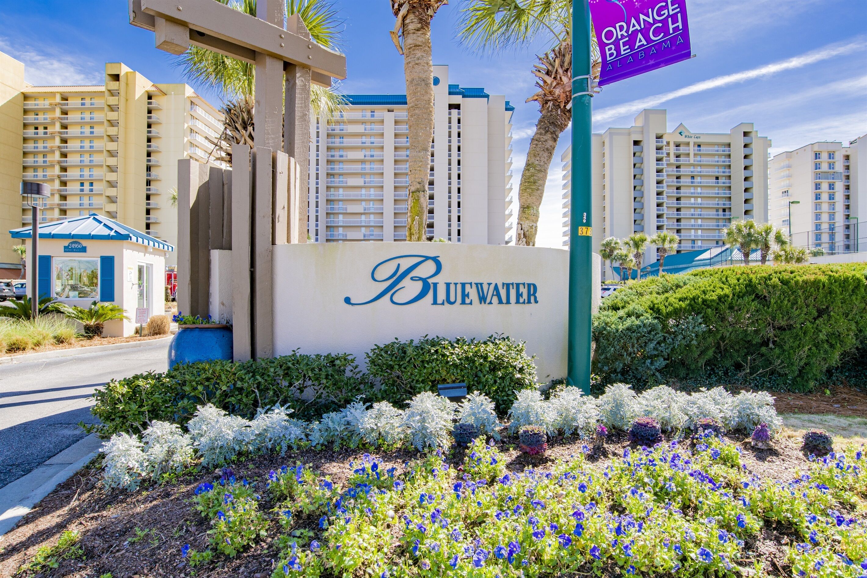 A Bluewater hotel sign with a view of high-rise buildings and a sign for Orange Beach, Alabama.