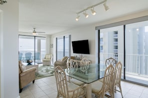 Relax in this stylish living area with a dining table, wicker chairs, and a flat-screen TV.