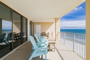 Relax on the balcony with ocean views, featuring Adirondack chairs and a small table.