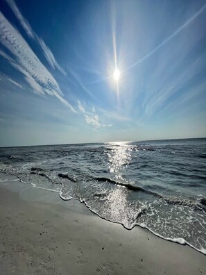 Ein Strand mit Wellen, blauem Himmel und Sonnenschein.