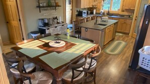A spacious kitchen with wooden cabinets, a central island, and a dining area with chairs. - Luxury Waterfront Log Cabin ... Memories Abound (Crivitz)