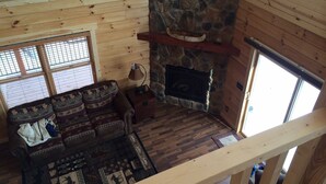 A cozy cabin interior with a stone fireplace, wooden walls, a patterned sofa, and a wooden floor. - Luxury Waterfront Log Cabin ... Memories Abound (Crivitz)