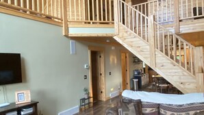 A spacious living area with a high ceiling, wooden staircase, and a cozy sofa. - Luxury Waterfront Log Cabin ... Memories Abound (Crivitz)