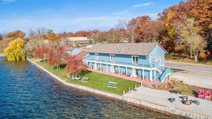 A waterfront building with a clear view of the water, a grassy area, and a paved walkway.