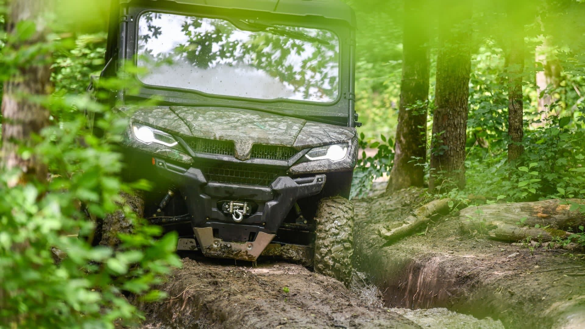 A vehicle navigating a muddy terrain in a forested area.