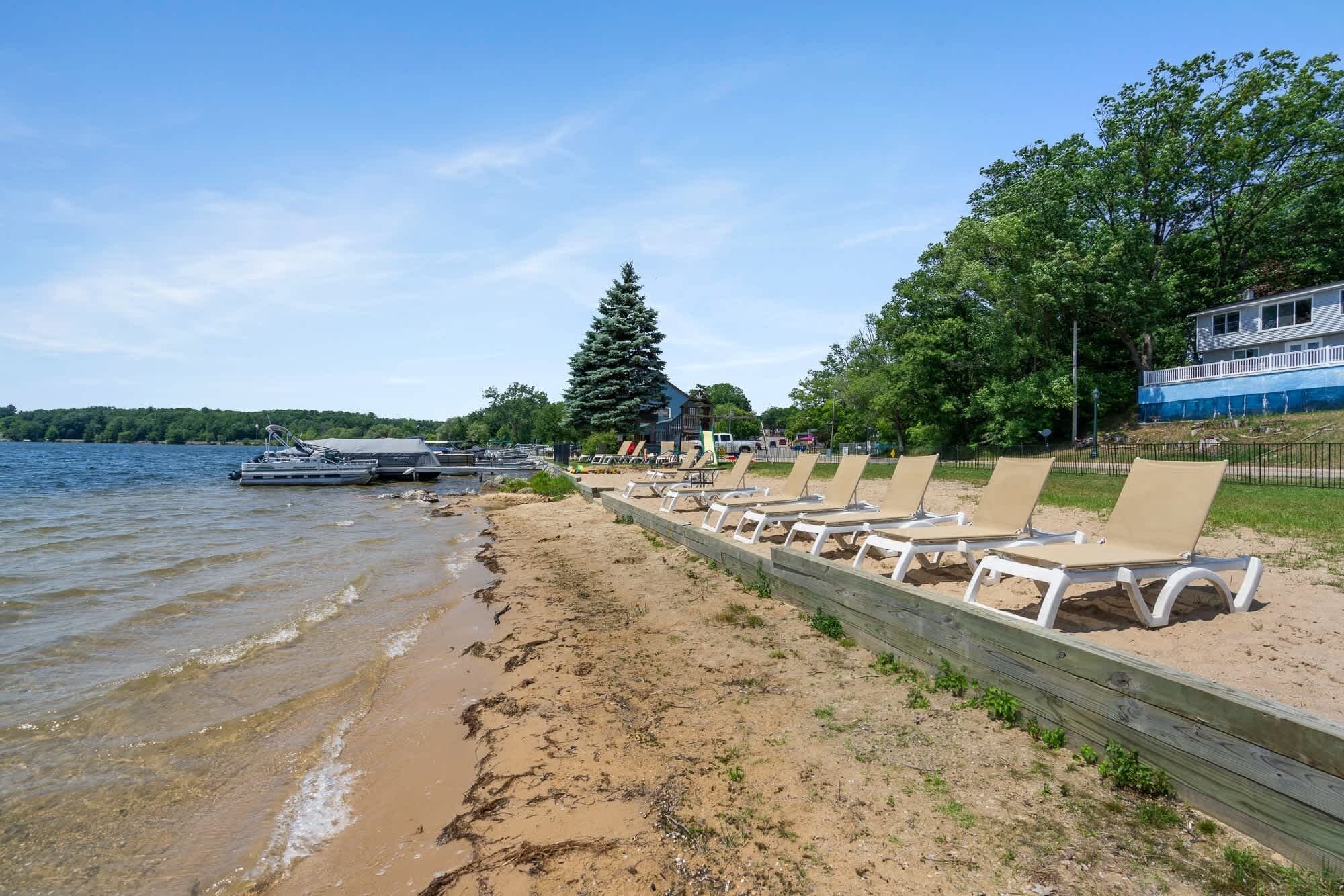Ein Strand mit Liegestühlen, einem Holzzaun und einem Boot, das an der Wasserkante liegt.