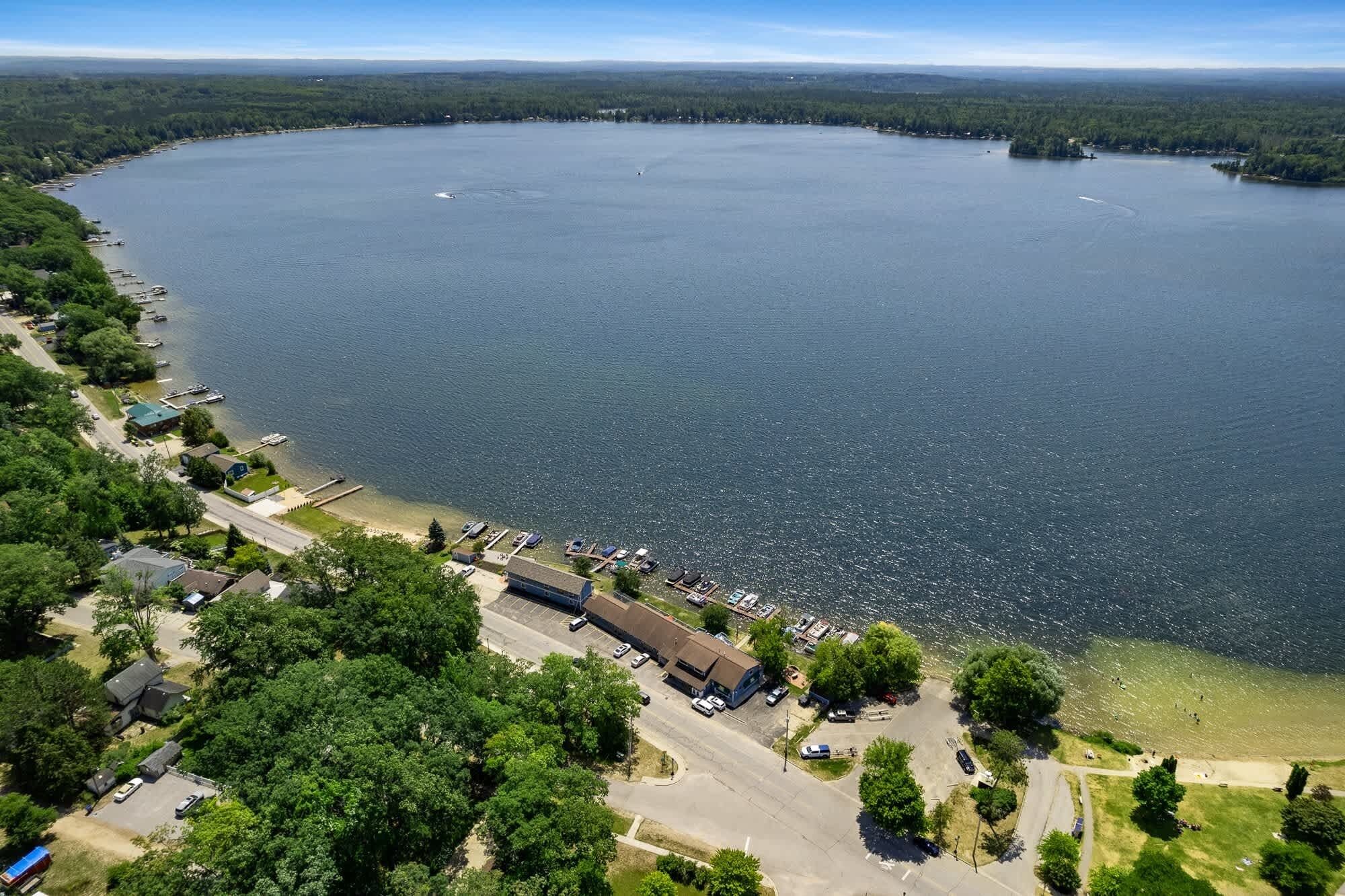An aerial view of a lakeside property with a marina, parking area, and buildings.