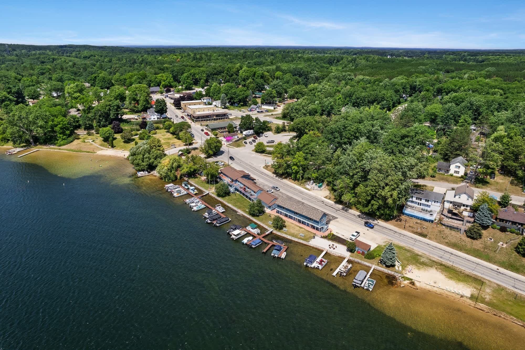 An aerial view of a lakeside community with a marina, residential buildings, and a road.
