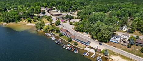 An aerial view of a lakeside community with a marina, residential buildings, and a road.