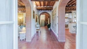 A corridor with a tiled floor, brick arches, and wooden beams on the ceiling. - Villa Dondolino, a Stylish Farmhouse with Private Pool close to Lucca and the Beach (Lucca)