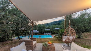 A patio area with outdoor furniture, a pool, and a hanging chair. - Villa Dondolino, a Stylish Farmhouse with Private Pool close to Lucca and the Beach (Lucca)