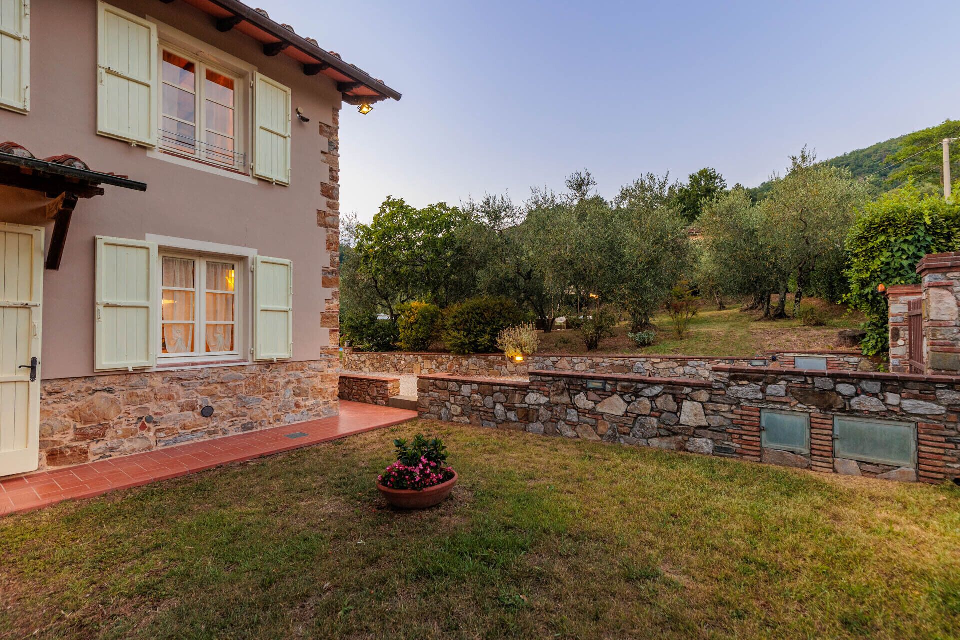 A two-story house with stone walls and a stone pathway leading to the entrance.