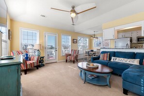 A living room with a blue sofa, striped armchairs, a coffee table, and a ceiling fan.