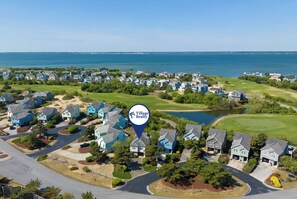 An aerial view of a residential area with houses, roads, and a body of water in the background.