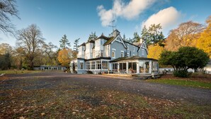 Een groot, twee verdiepingen tellend huis met een veranda en een overdekte zithoek buiten.