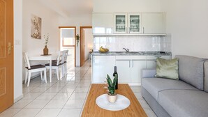 A modern kitchen with white cabinets, a dining area with a table and chairs, and a living area with a sofa and a coffee table. - Beautiful spacious apartment (No. 1) with 2 bedrooms 300m to the beach (Poreč)