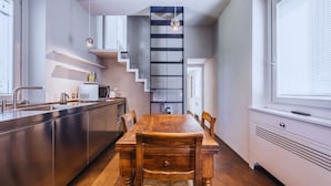 A modern kitchen with a wooden dining table, stainless steel appliances, and a staircase leading to an upper level. - Country House with heated pool near the center (Firenze)
