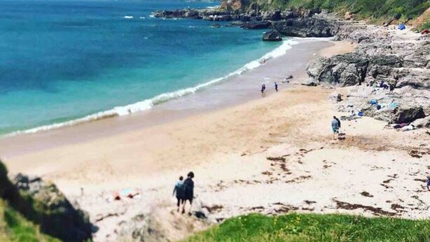 Una playa costera con terreno rocoso y una vista despejada del mar.