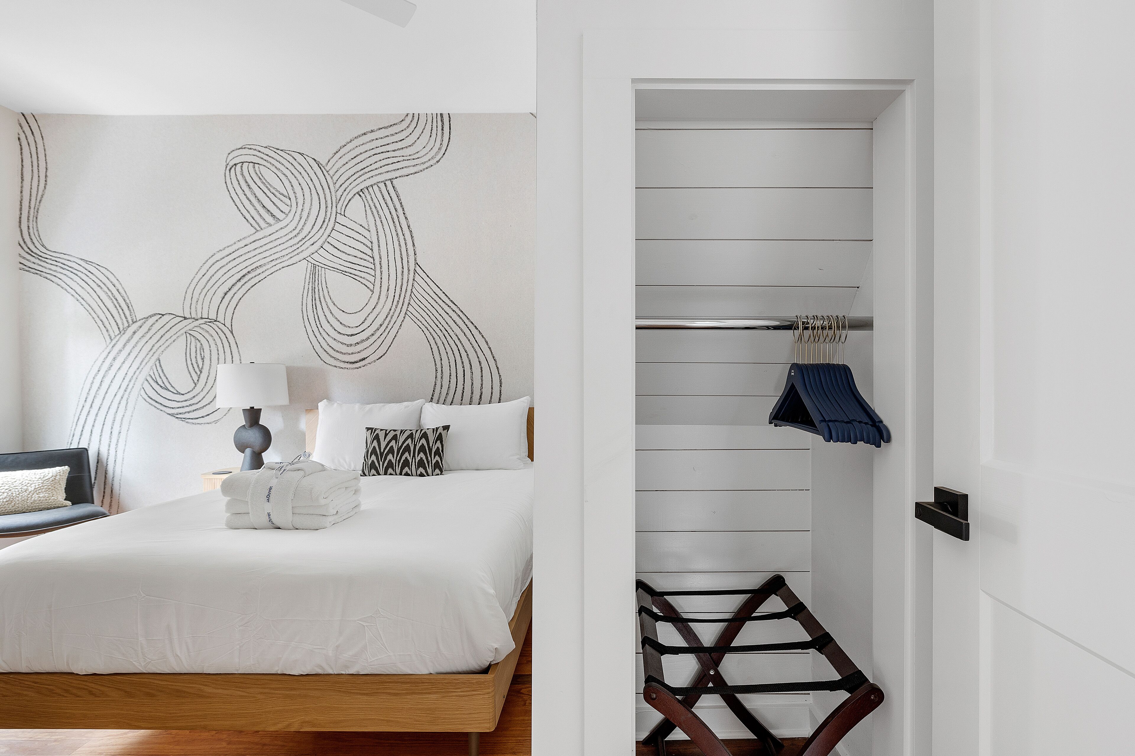 Una camera d'albergo moderna con un letto rifatto, un'opera d'arte a parete e un pavimento in legno.