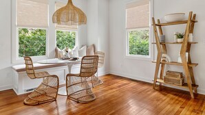 A bright room with a wooden floor, a dining table with chairs, a hanging light, and a wooden shelf with items. - Prime Location in Park Circle | The Aloha Cottage (North Charleston)