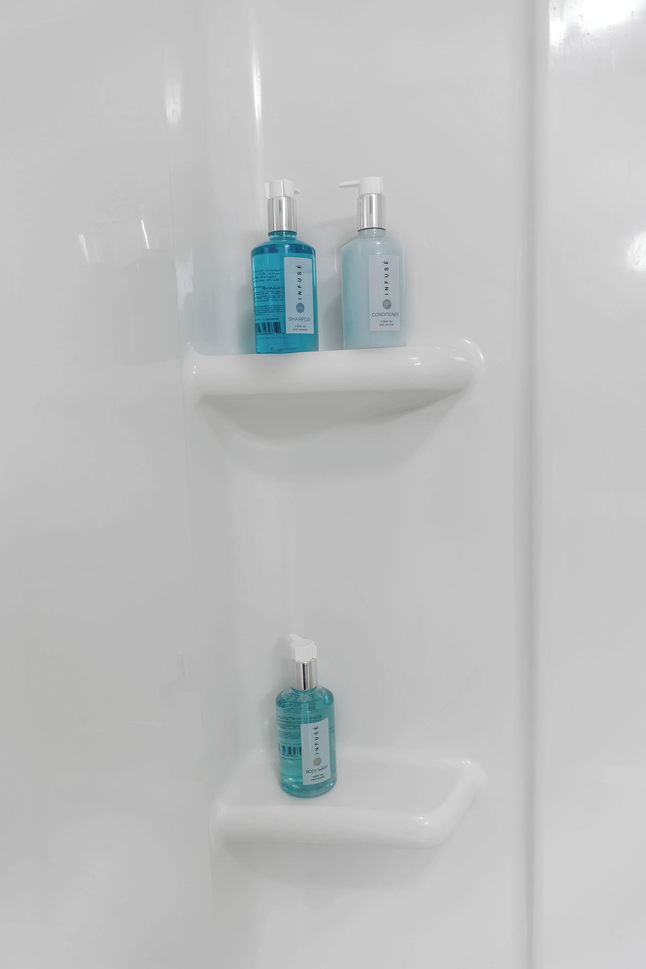 Une salle de bain aux murs blancs, avec trois étagères où sont rangés divers produits de toilette.