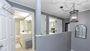 A hallway with a white door, a mirror, and a light fixture. - Large 3 floor Townhome with Patio, Backyard and Sauna (Manchester)