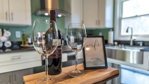 A kitchen counter with two wine glasses, a wine bottle, and a framed picture. - Large 3 floor Townhome with Patio, Backyard and Sauna (Manchester)