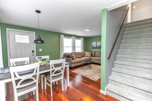 Un salon comprenant un coin repas, un escalier et un mur végétal.