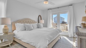 A bedroom with a large bed, a ceiling fan, and a view of the outside. - The Shady Lady: Spacious Ocean View Home with Open Floorplan (Oak Island)
