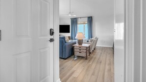 A modern living room with a sofa, a coffee table, and a TV. - The Shady Lady: Spacious Ocean View Home with Open Floorplan (Oak Island)