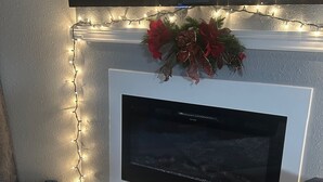A fireplace with a flat-screen TV mounted above it, surrounded by string lights and a decorative wreath. - Ridgeline Views, Private Deck, 2 Kings, Kid-Friendly, Pointe Royale Resort (Branson)
