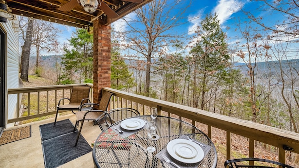 A covered outdoor patio with a table set for dining, overlooking a scenic view of trees and a body of water. - Ridgeline Views, Private Deck, 2 Kings, Kid-Friendly, Pointe Royale Resort (Branson)