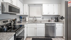 A modern kitchen with white cabinets, stainless steel appliances, a granite countertop, and a built-in oven. - Ridgeline Views, Private Deck, 2 Kings, Kid-Friendly, Pointe Royale Resort (Branson)