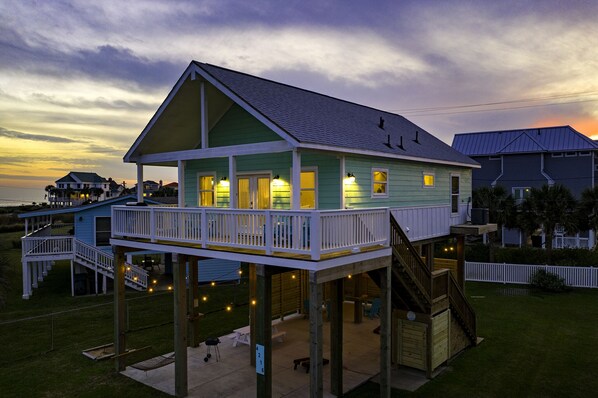 A two-story house with a balcony and a deck, featuring a staircase and outdoor seating area.