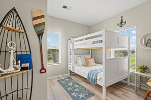 A bunk bed room with a nautical theme, including a ship decoration and a starfish rug.
