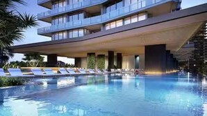 A modern hotel with a swimming pool, lounge chairs, and a multi-story building. - Signature 2B2B Stunning Chic Guest Fav +OceanView (Broadbeach)