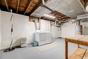 Basement room with a functional layout, featuring a washing machine, table, and radiator.