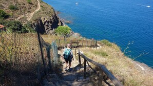 Une personne qui fait de la randonnée sur un sentier rocheux, avec une vue sur la mer.