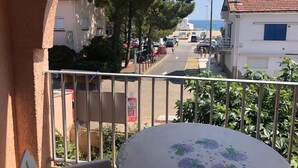 Un balcon donnant sur une rue, des immeubles et un ciel dégagé.