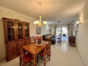 A spacious living area with a dining table, chairs, a sofa, and a chandelier.