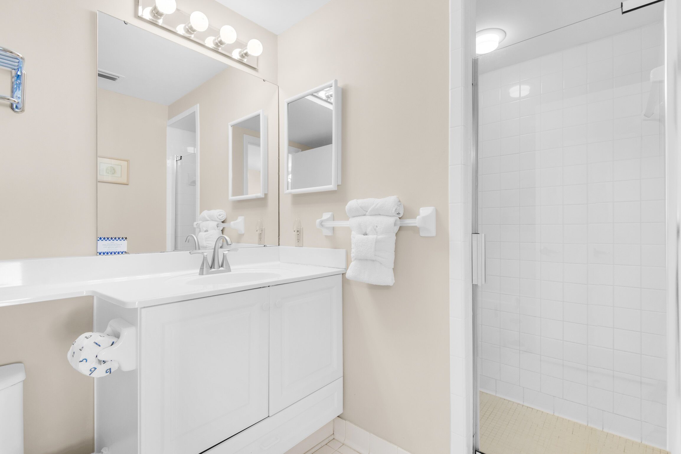 Un baño moderno con un lavamanos blanco, un espejo y un perchero para toallas.