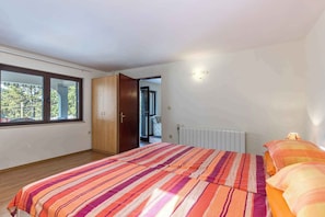 Een slaapkamer met een groot bed, een kledingkast, een raam en een radiator.