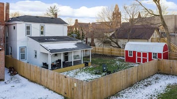 Een woonhuis met omheinde achtertuin, een losstaande garage en een woning met veranda.