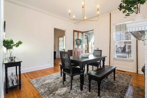 A dining area with a dark wooden table, chairs, and a chandelier.